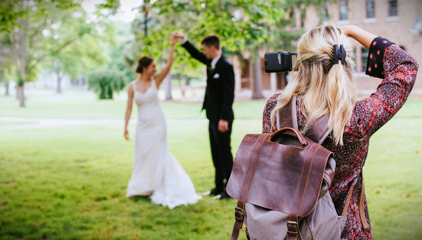 Photographer taking a picture of the bride and groom outdoors